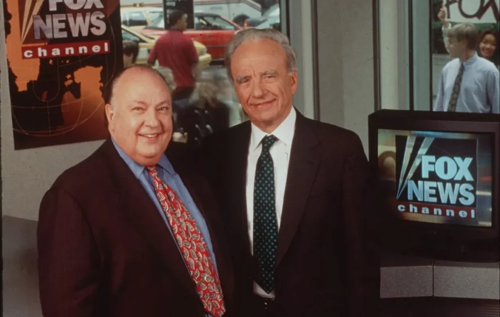 Rupert Murdoch and Roger Ailes standing together in front of Fox News branding in 1996.
